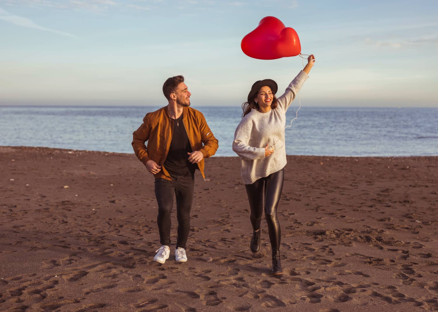 happy-couple-running-sea-shore-with-heart-balloons